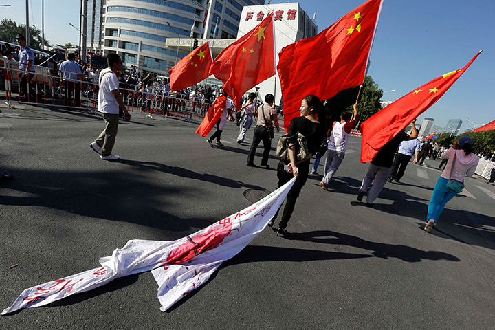 Anti-Japan protests: A woman drags a Japanese flag