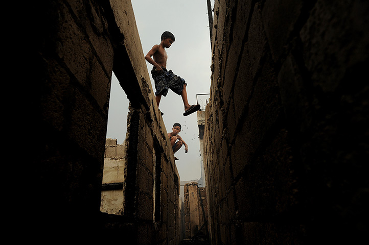 24 hours in pictures: Children walk above destroyed houses after a pre-dawn fire engulfed a slum