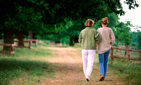 Mother and daughter walking arm in arm along trail