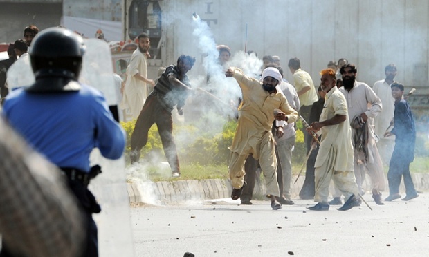 A Pakistani demonstrator throws a tear gas shell towards riot police during a protest against an anti-Islam film in Islamabad. Demonstrators set fire to two cinemas in Pakistan's northwestern city of Peshawar, police and witnesses said.