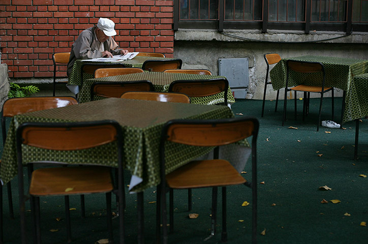 Kosovo art installation: An old man reads a newspaper outside a cafe