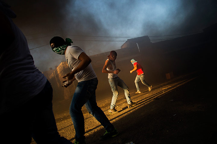 Twenty Photographs: Masked Palestinians throw stones at Israeli security forces in Shuafat refugee camp, Jerusalem