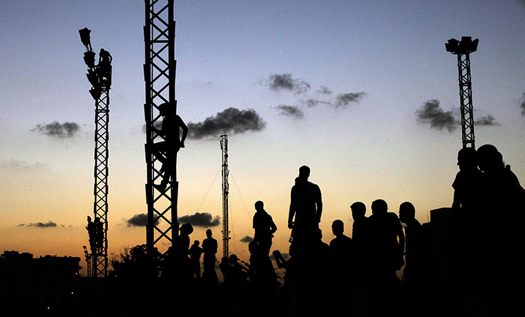 24 Hours: People in Benghazi, Libya, climb electricity towers to watch a march against Ansar al-Sharia militia