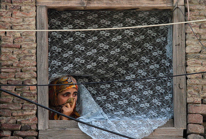 24 hours: Srinagar, India: A Kashmiri Muslim watches from the window