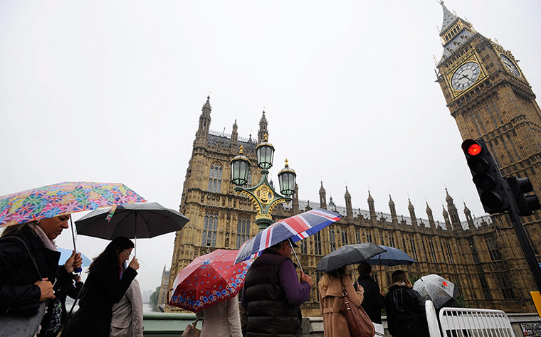 24 hours: London, England: Pedestrians shelter under umbrellas