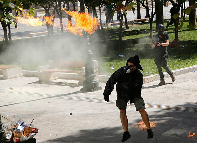 Greece protests update: A demonstrator throws a molotov cocktail to riot police officers