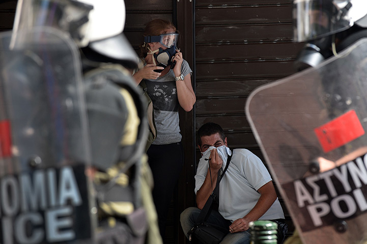 Greece protests updates: Demonstrators take shelter and react to teargas shot