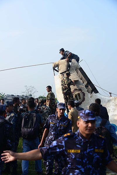 Nepal plane crash: Nepalese rescue team members climb the tail of the plane