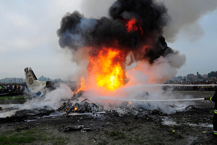 Nepal plane crash: Rescue team members douse the aircraft