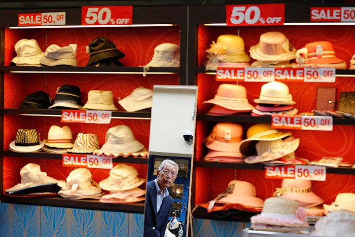 24 hours in pictures: A man is reflected in a mirror near a shop selling hats at a market in Tokyo