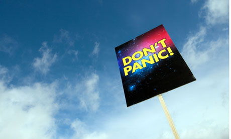 A Don't Panic placard pictured against a blue sky with white clouds.