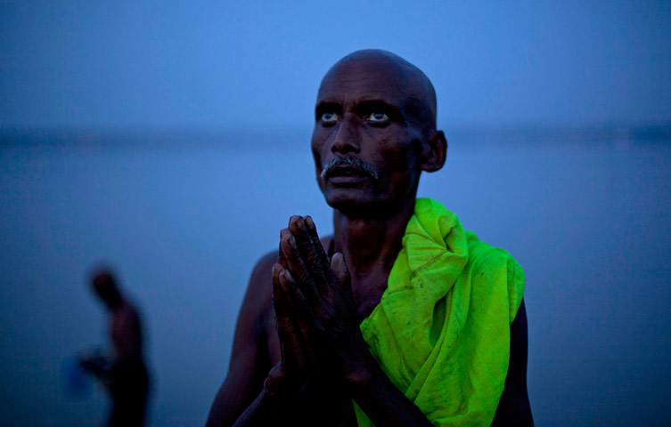 24 hours: A Hindu devotee performs evening rituals on the banks of the River Ganges