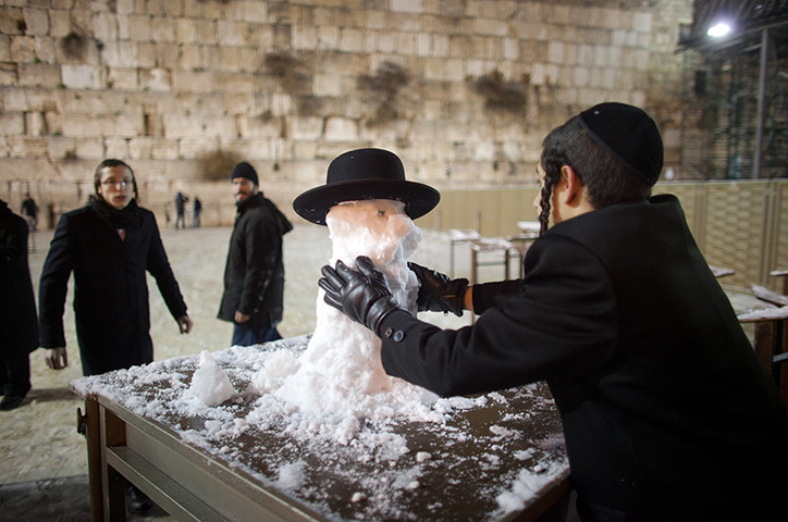 Snow in Jerusalem: An ultra-Orthodox Jewish boy builds a snowman