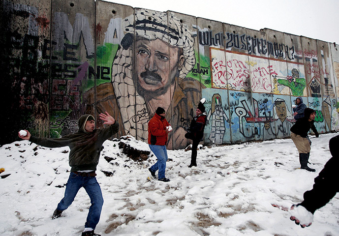 Snow in Jerusalem: Palestinians play in the snow next to a section of Israel's barrier