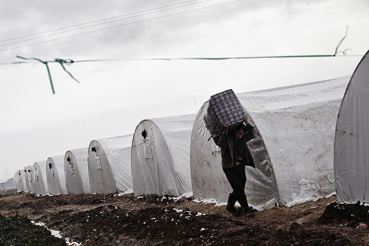 24 hours in pictures: A Syrian refugee man carries a bag at a refugee camp 
