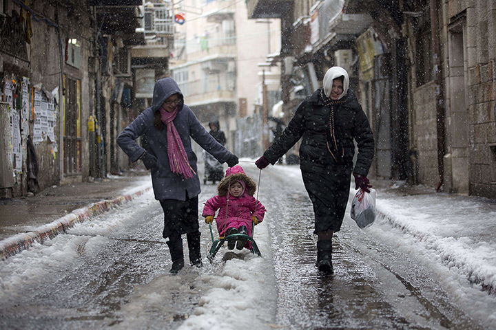 Snow in Jerusalem: A girl enjoys sledging on an icy road