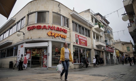 A Cypriot woman carrying grocery bags walks past a supermarket in the old city of Nicosia on December 20, 2012.