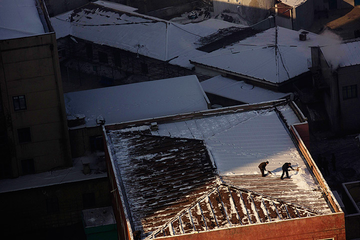24 hours in pictures: North Korean men shovel snow from the roof