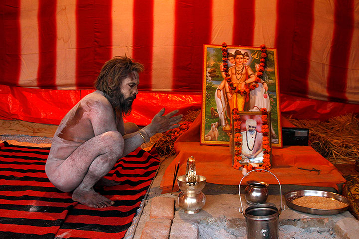 24 hours: A Naga sadhu, or naked Hindu holy man, prays inside his camp at the Sangam