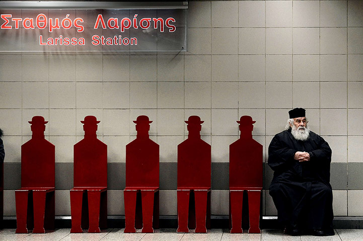 24 hours: A Greek Orthodox priest sits on a train platform
