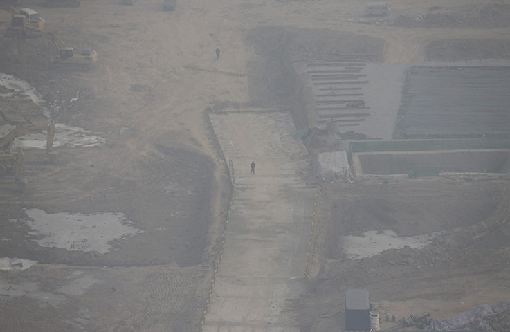 Air Pollution in China: Workers walk at a construction site in the heavy haze in Beijing