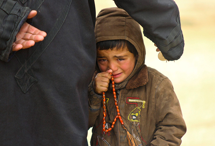 24 hours: Idlib, Syria: A boy stands next to his father and cries