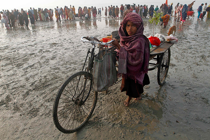 24 hours: Sagar Island, India: A girl pulls a tricycle loaded with religious material