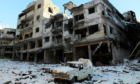 A damaged car and buildings in Homs