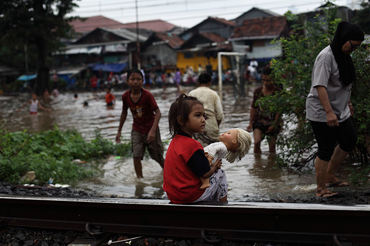24 hours in pictures: Child holds a doll as she sits on a railway track near flood