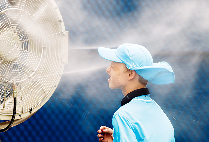 24 hours in pictures: A ball boy cools off in front of fans at Melbourne Park