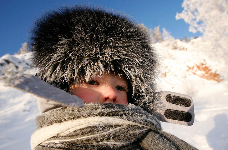 24 hours in pictures: Hoarfrost covers the fur cap and scarf of a child 