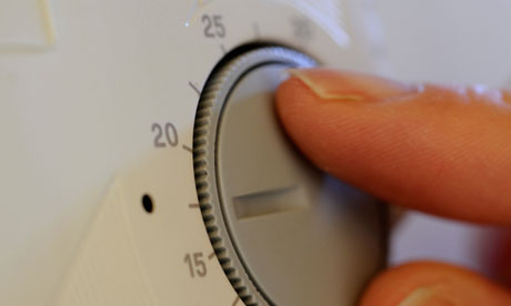 Woman turning doen domestic heating thermostat. Image shot 2009. Exact date unknown.