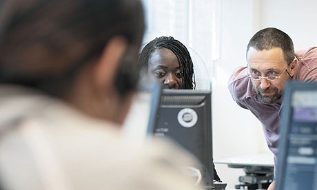 Young apprentice working at computer with mentor