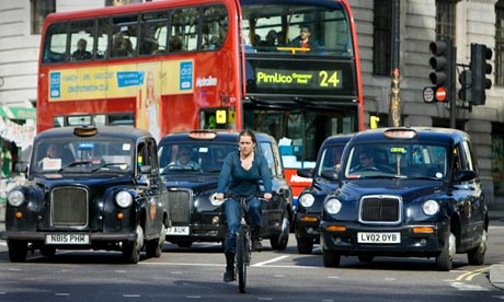 Woman cycles in London traffic