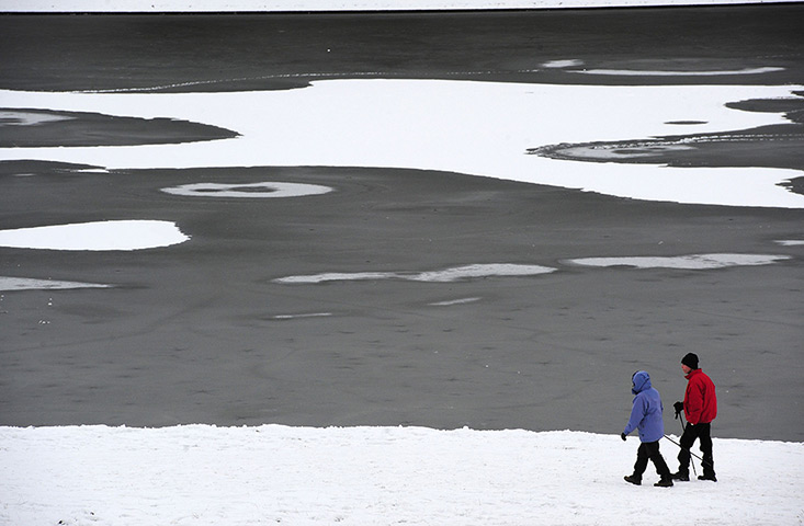 Snowy weather: Ripon: People walk around the partially frozen lake at Studley Royal Park