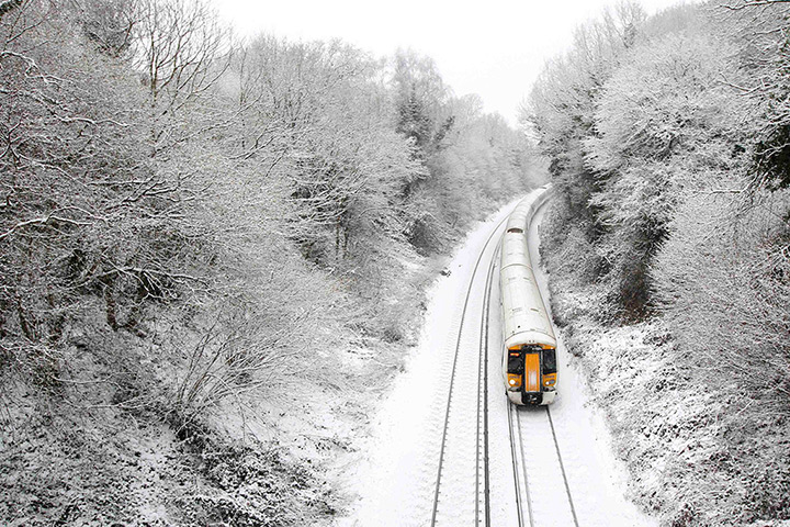 Snowy weather: Crowhurst A train travels through countryside covered in snow