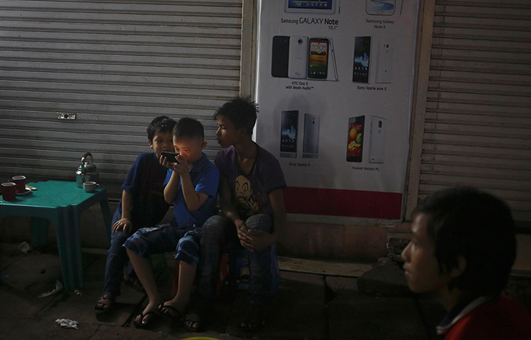 24 hours: Rangoon, Burma: Children use a mobile phone