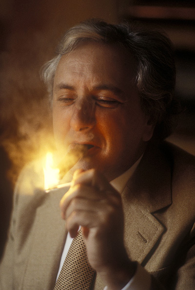 michael winner: Michael Winner lights a cigar in 1982