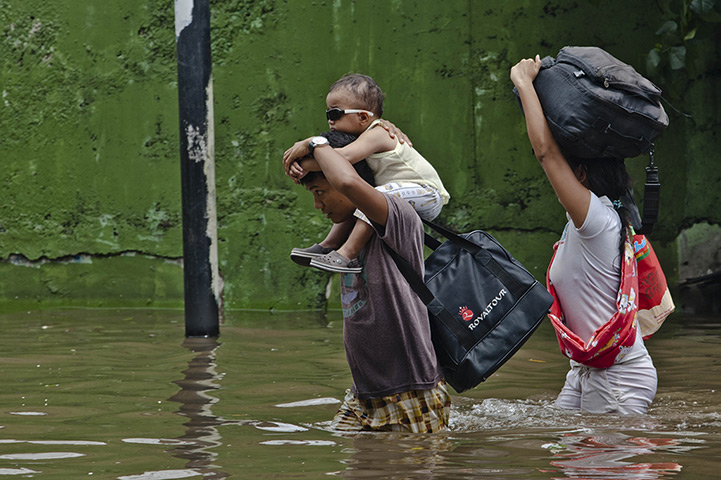 FTA: Ulet Ifansasti: A man carries his son as he makes his way through floodwaters 