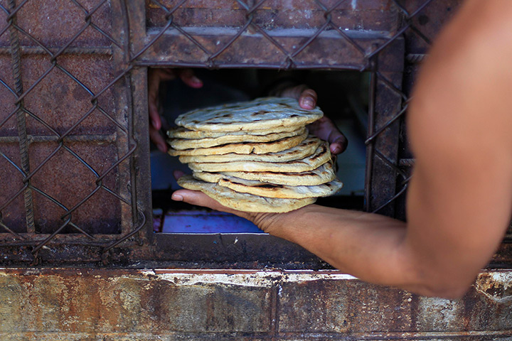 24 hours in pictures: An inmate receives a stack of tortillas at a jail in Tonacatepeque