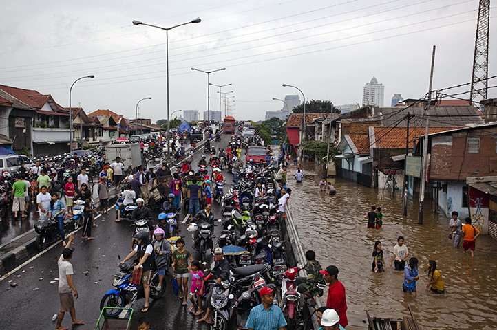 FTA: Ulet Ifansasti: People gather on  a road as others wade through floodwaters