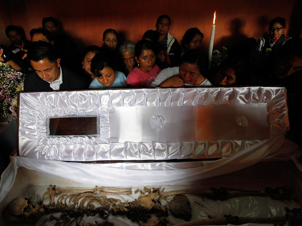 People look at the skeleton of Roberto Enrique Cac Suc inside a coffin in San Cristobal Verapaz