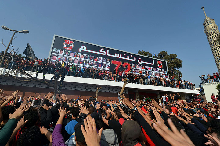 Egypt football trial: Al Ahly fans celebrate in front of a billboard bearing pictures of the riot victims