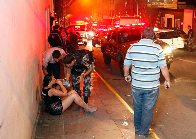 Rio nightclub: A police officer helps a woman next to Kiss nightclub