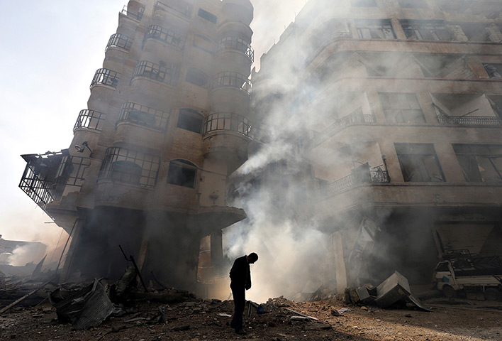 24 hours: A man walks in front of a burning building in Damascus