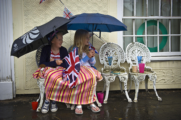 Wet UK weather 2012 : June: Spectators sheltering from rain as they wait for the Olympic Flame