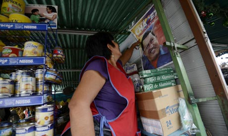 A woman fixes a poster of Hugo Chavez