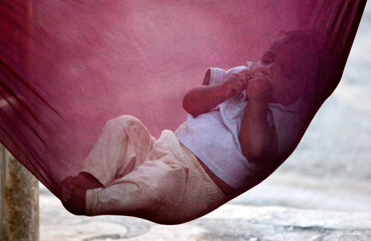 24 Hours: Mumbai, India: An Indian child sleeps nestled in a cloth hammock