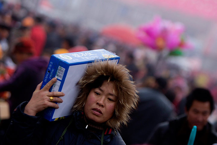 24 Hours: Qingdao, China: A woman carries goods at a market in Shandong province