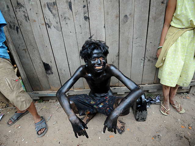 24 hours in pictures: A youngster smeared with used car oil rests during a ball game